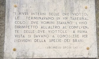 Citazione targa del tabernacolo dei Bravi, rione Acquate: "I muri interni delle due viottole... terminavano in un tabernacolo... due uommini stavano l'uni dirimpetto all'altro, al confluente... delle due viottole... a prima vista si davano a conoscere per individui della specie dei Briavi" (Promessi sposi, Cap. 1)